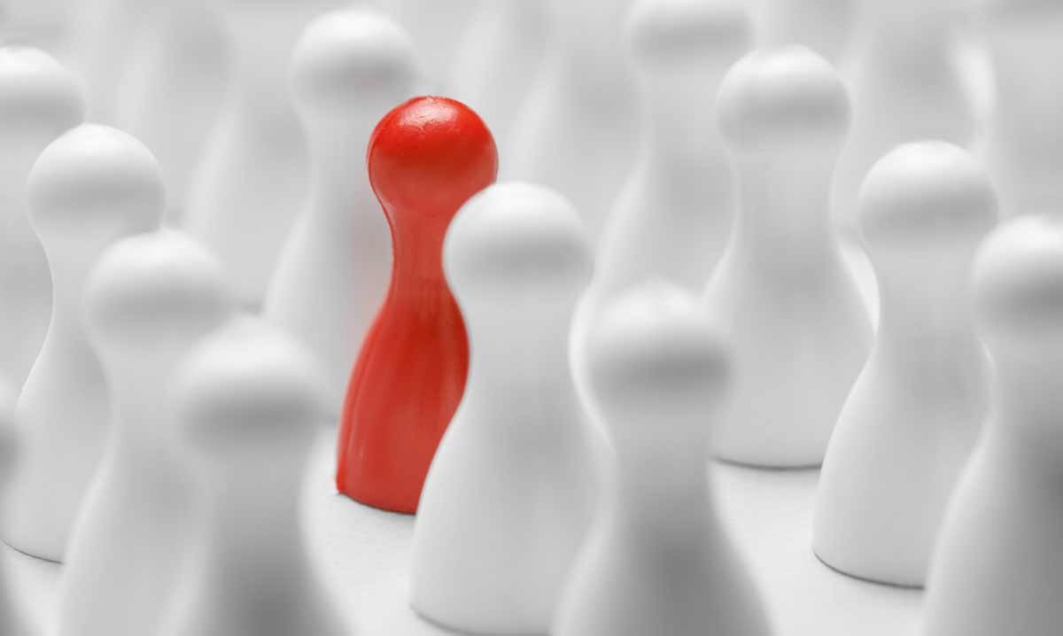 Red chess pawn in the middle of a bunch of white pawns